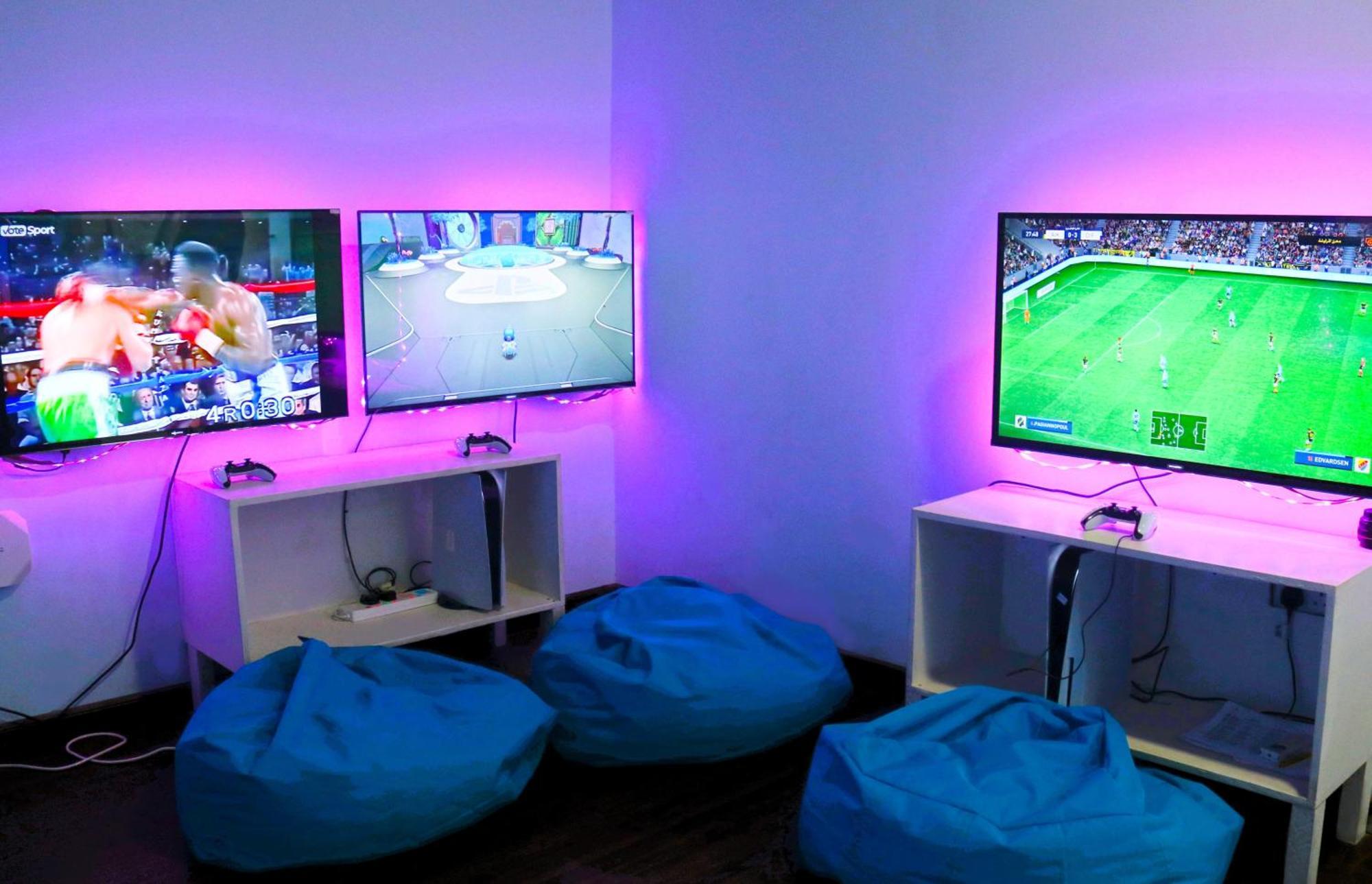 Lagoona Beach Luxury Resort And Spa Манама Екстер'єр фото The photo shows a gaming area featuring three televisions mounted on the wall, displaying different games. Two of the TVs are showing gaming scenes, with one depicting a boxing game and the other showing a vibrant game environment. The third TV displ
