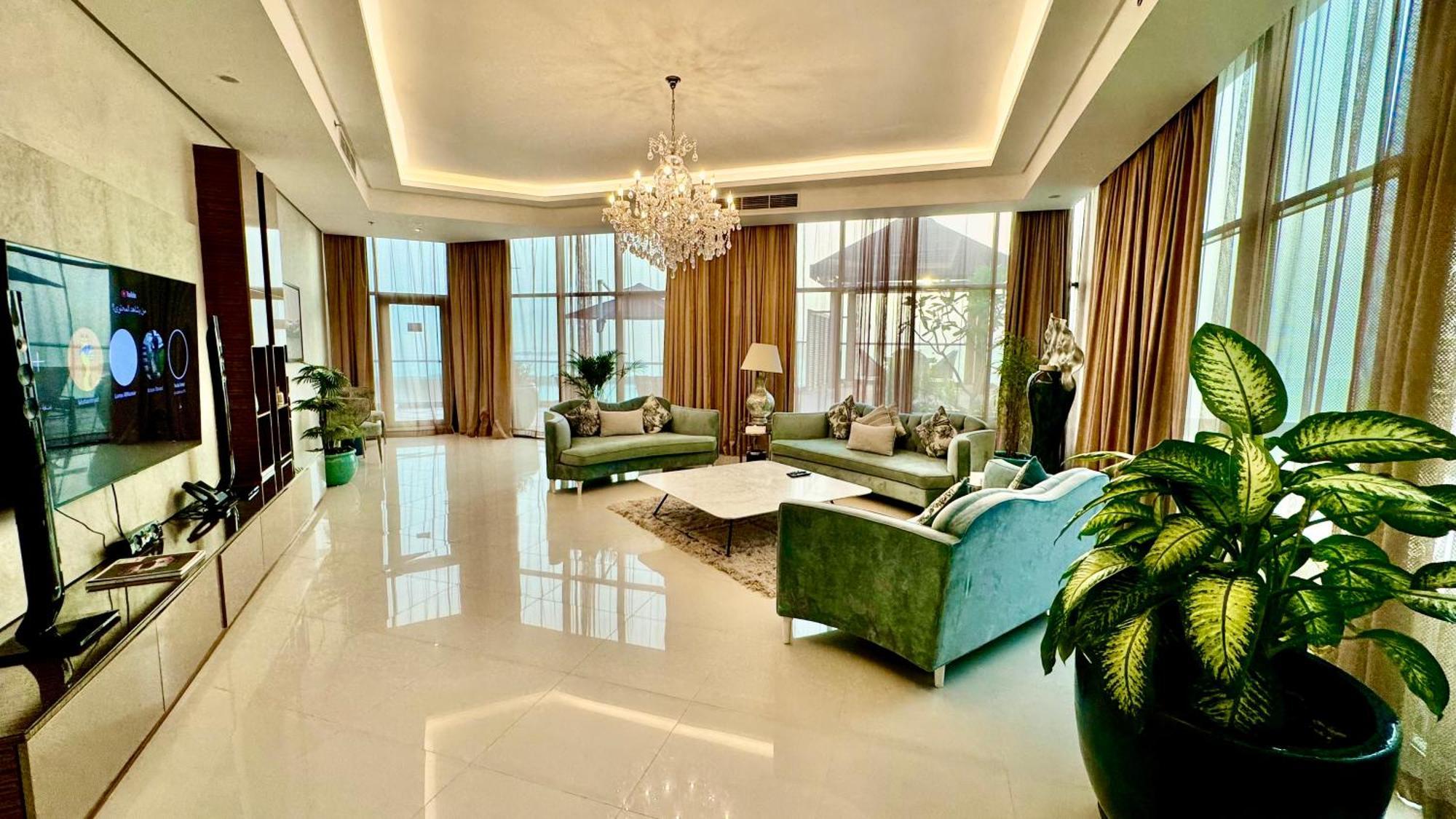 Lagoona Beach Luxury Resort And Spa Манама Екстер'єр фото The photo depicts a spacious and elegantly designed living room. The room features large windows allowing natural light to flood in, accompanied by sumptuous curtains. The furniture includes a pair of soft green sofas and a centerpiece coffee table s