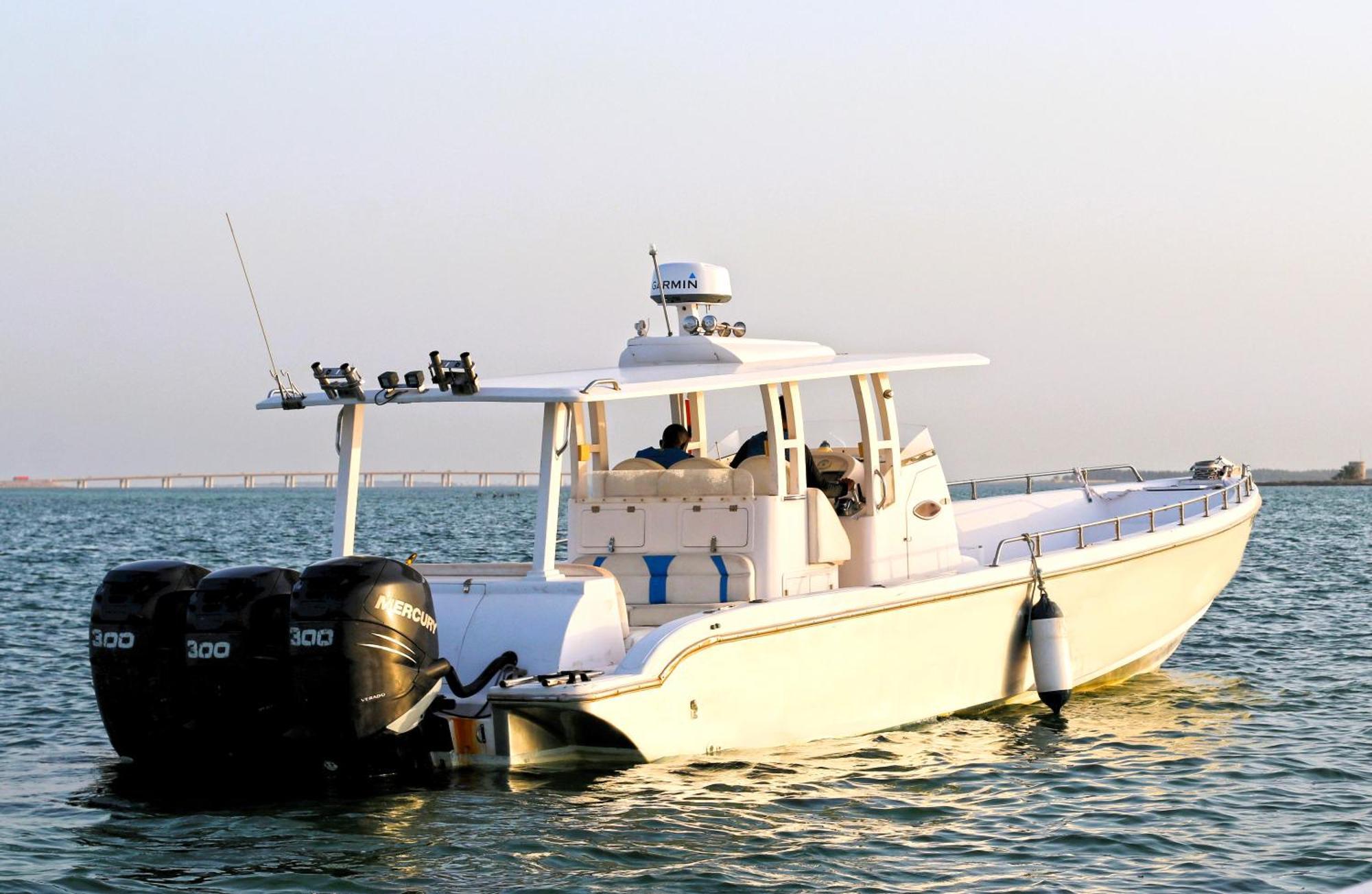Lagoona Beach Luxury Resort And Spa Манама Екстер'єр фото The photo shows a large, white motorboat equipped with three powerful outboard engines at the stern. The boat has a sleek design, with a spacious open deck and a covered cabin area that likely provides shelter and controls for navigation. The scene i