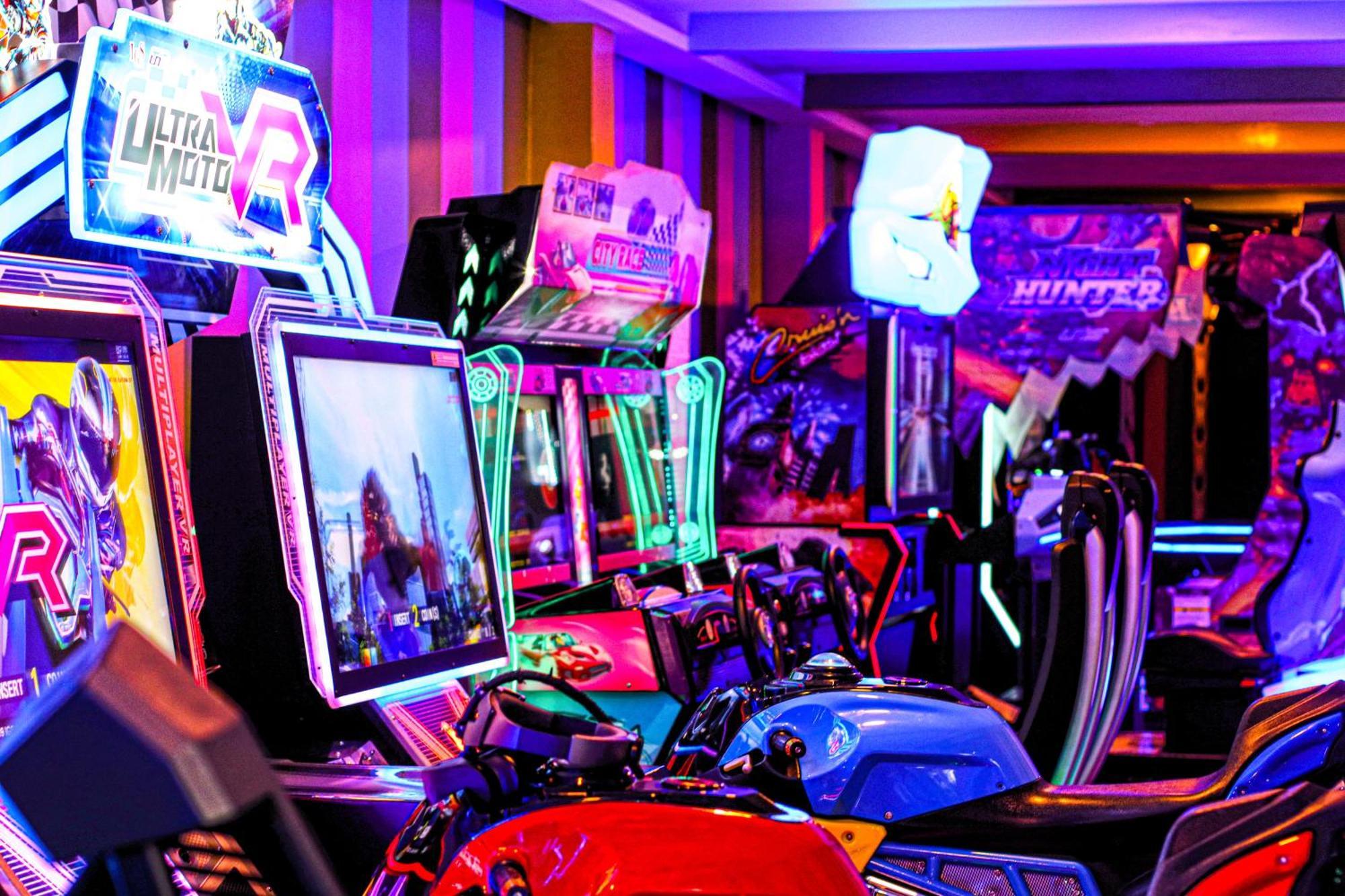 Lagoona Beach Luxury Resort And Spa Манама Екстер'єр фото The photo shows a vibrant arcade scene featuring various arcade gaming machines. The machines are lined up, showcasing colorful screens and bright, neon lights, creating an energetic atmosphere. Some machines appear to be racing games, as indicated b