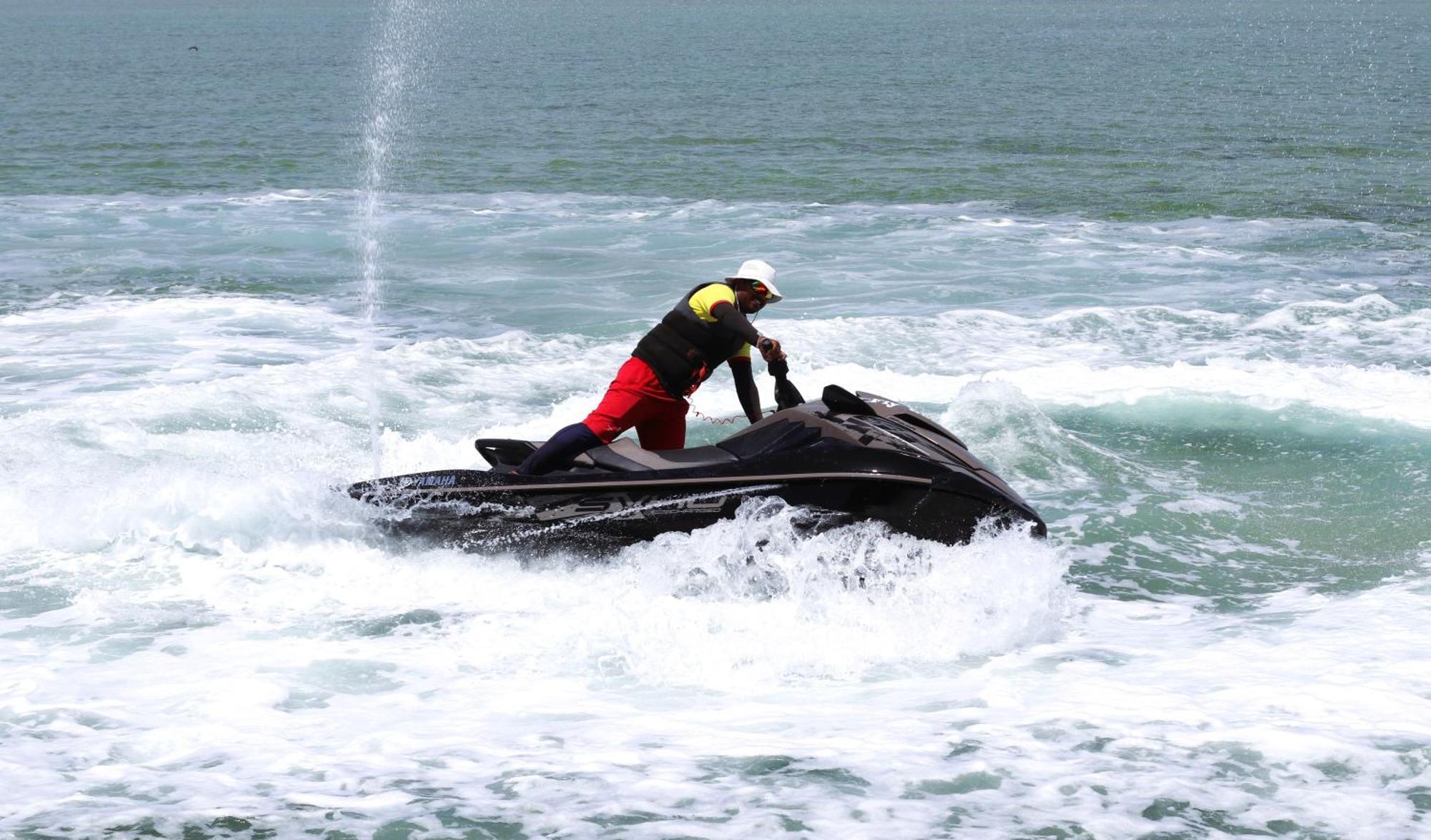 Lagoona Beach Luxury Resort And Spa Манама Екстер'єр фото The photo shows a person riding a jet ski on the water. The rider is positioned upright, leaning forward with one hand on the handlebars, while the jet ski creates splashes of white foam around it. The water appears choppy, likely due to the motion o