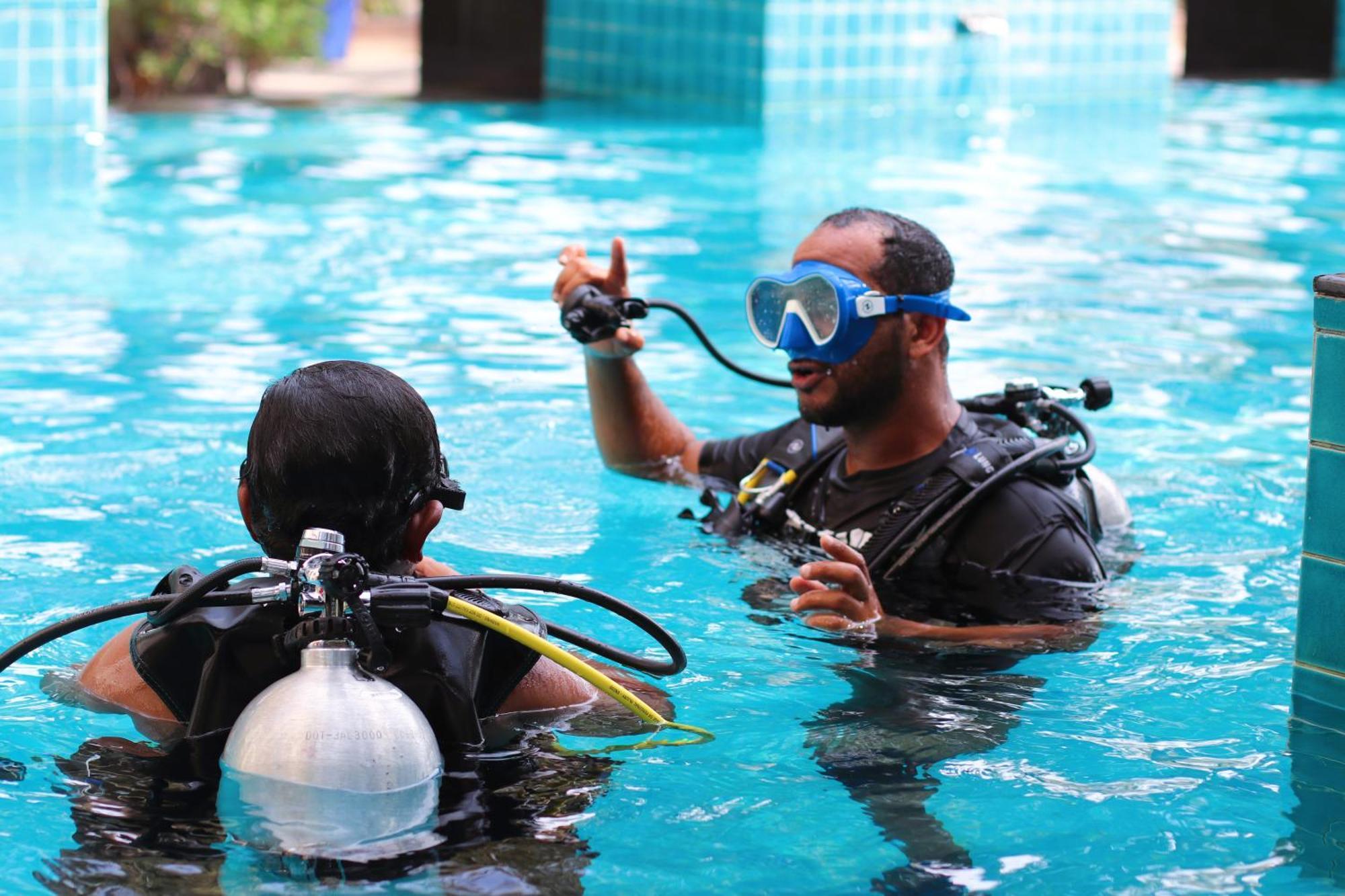 Lagoona Beach Luxury Resort And Spa Манама Екстер'єр фото The photo shows two divers in a pool. One diver is wearing a scuba mask and is speaking to the other diver, who is also equipped with scuba gear. They appear to be engaged in a discussion, possibly related to diving instructions or safety. The water 